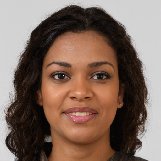 Joyful black young-adult female with long  brown hair and brown eyes