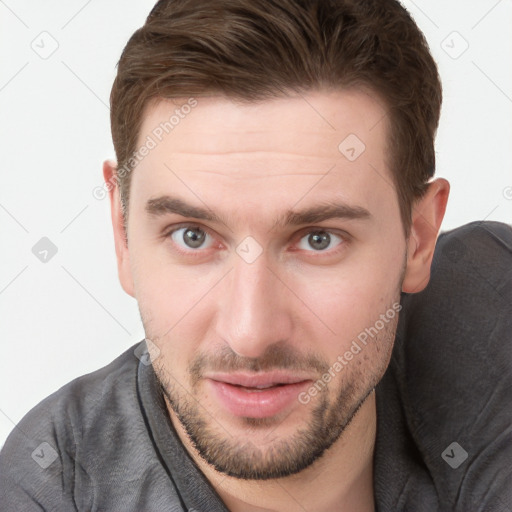 Joyful white young-adult male with short  brown hair and grey eyes