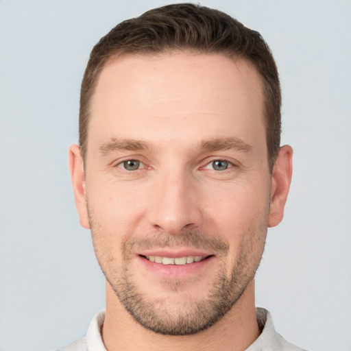 Joyful white young-adult male with short  brown hair and grey eyes