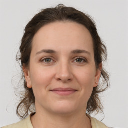 Joyful white young-adult female with medium  brown hair and grey eyes