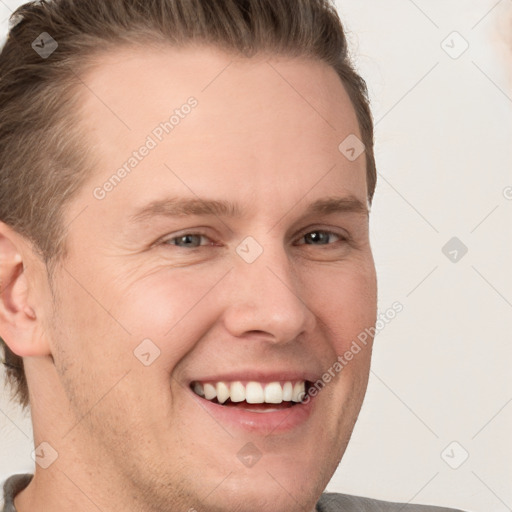 Joyful white young-adult male with short  brown hair and grey eyes