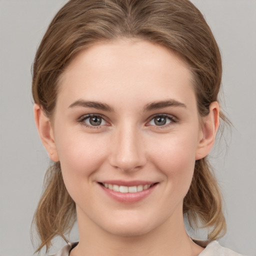 Joyful white young-adult female with medium  brown hair and grey eyes