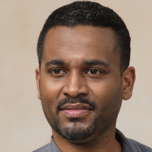 Joyful black young-adult male with short  black hair and brown eyes