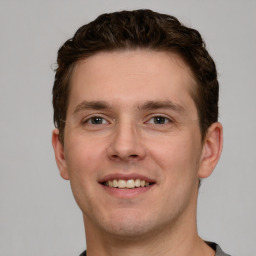 Joyful white young-adult male with short  brown hair and grey eyes