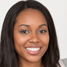 Joyful black young-adult female with long  brown hair and brown eyes