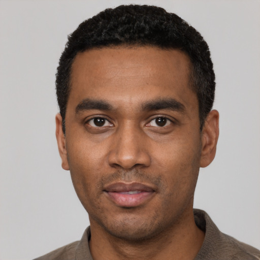 Joyful black young-adult male with short  black hair and brown eyes