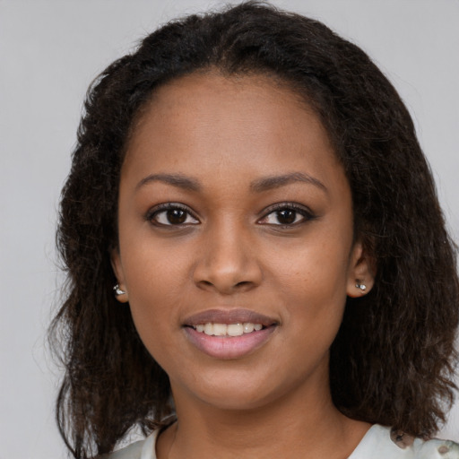 Joyful black young-adult female with long  brown hair and brown eyes