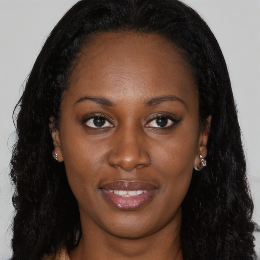 Joyful black young-adult female with long  brown hair and brown eyes
