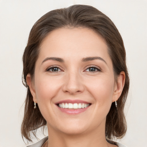 Joyful white young-adult female with medium  brown hair and grey eyes