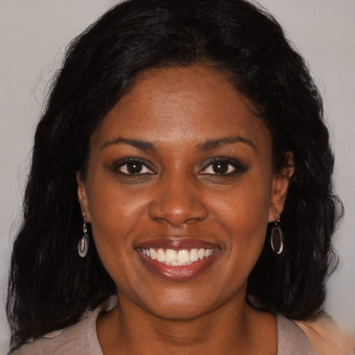 Joyful black young-adult female with long  black hair and brown eyes