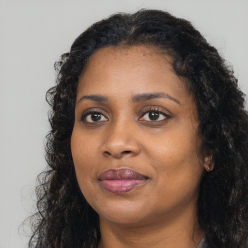 Joyful black young-adult female with long  brown hair and brown eyes