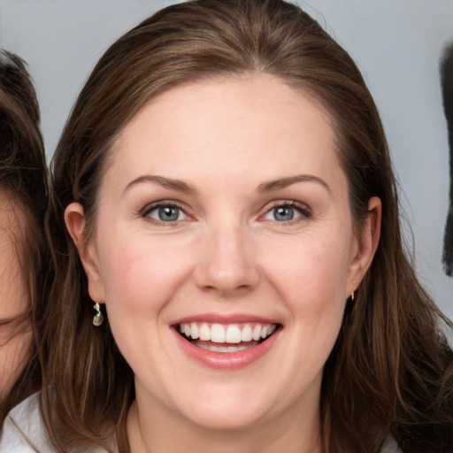 Joyful white young-adult female with long  brown hair and grey eyes