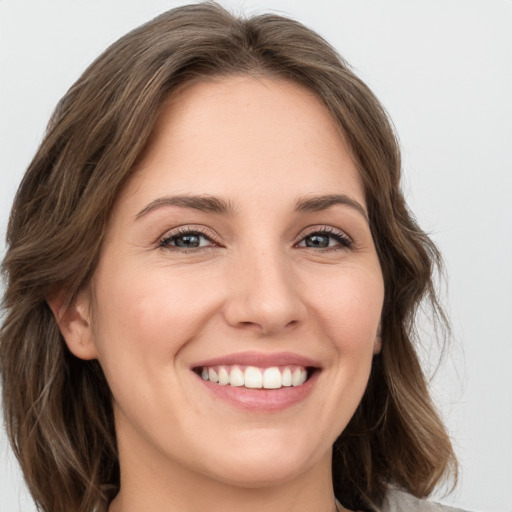 Joyful white young-adult female with long  brown hair and grey eyes