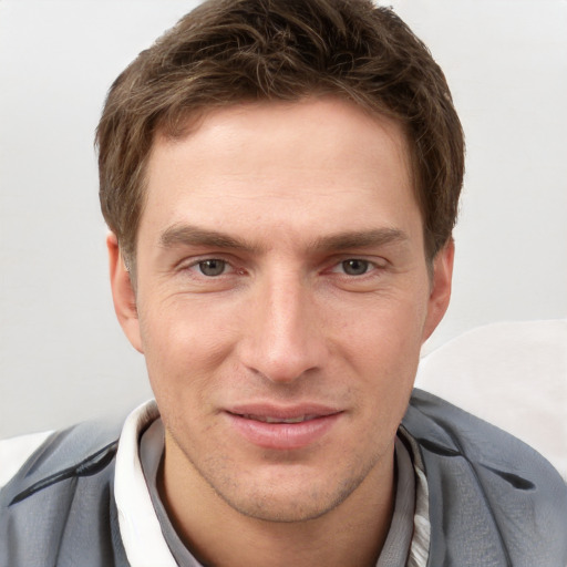 Joyful white young-adult male with short  brown hair and grey eyes