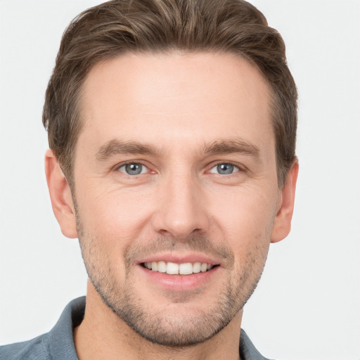 Joyful white young-adult male with short  brown hair and grey eyes