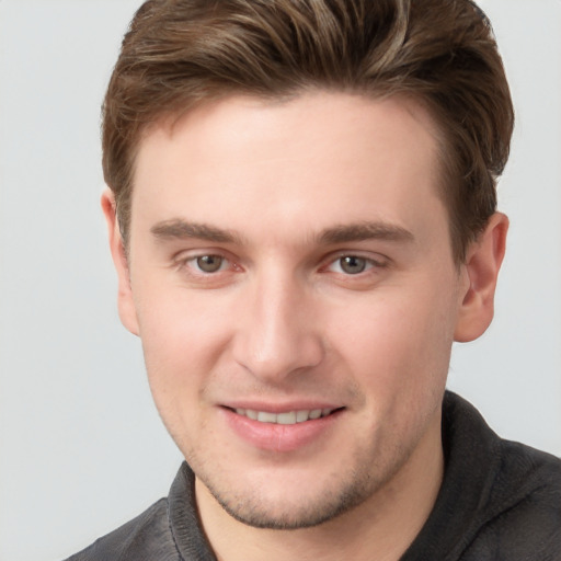 Joyful white young-adult male with short  brown hair and grey eyes