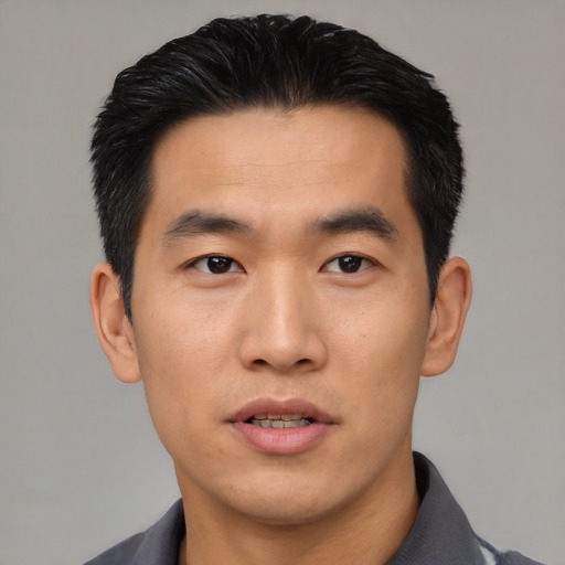 Joyful asian young-adult male with short  black hair and brown eyes