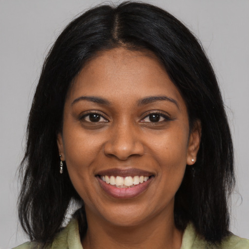 Joyful black young-adult female with long  black hair and brown eyes