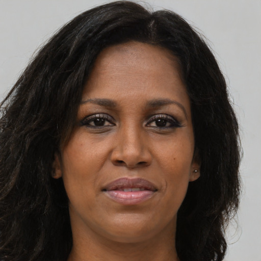 Joyful black young-adult female with long  brown hair and brown eyes