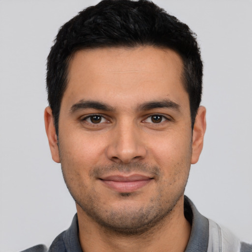 Joyful latino young-adult male with short  black hair and brown eyes