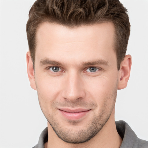 Joyful white young-adult male with short  brown hair and grey eyes