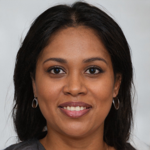 Joyful black young-adult female with long  brown hair and brown eyes