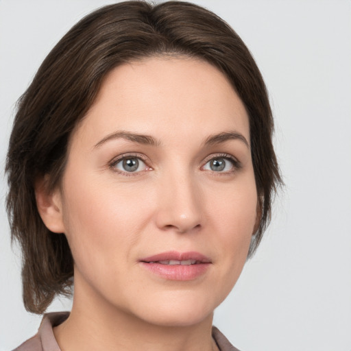 Joyful white young-adult female with medium  brown hair and grey eyes