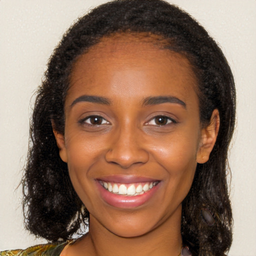 Joyful black young-adult female with long  brown hair and brown eyes