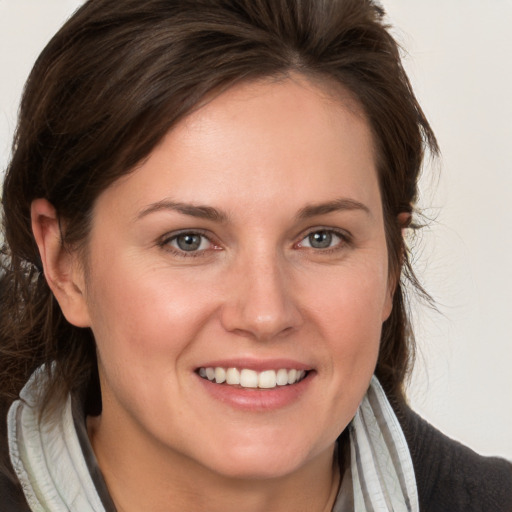 Joyful white young-adult female with medium  brown hair and grey eyes