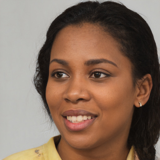 Joyful black young-adult female with long  black hair and brown eyes