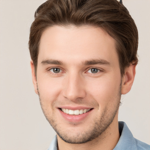 Joyful white young-adult male with short  brown hair and grey eyes