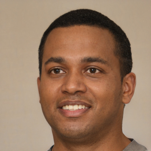 Joyful black young-adult male with short  black hair and brown eyes