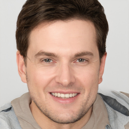 Joyful white young-adult male with short  brown hair and grey eyes