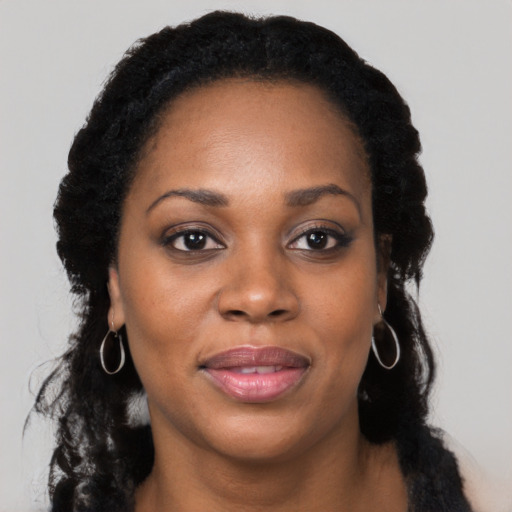 Joyful black young-adult female with long  black hair and brown eyes
