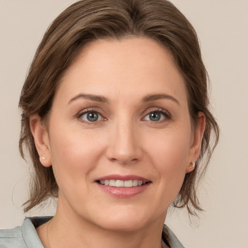 Joyful white young-adult female with medium  brown hair and grey eyes