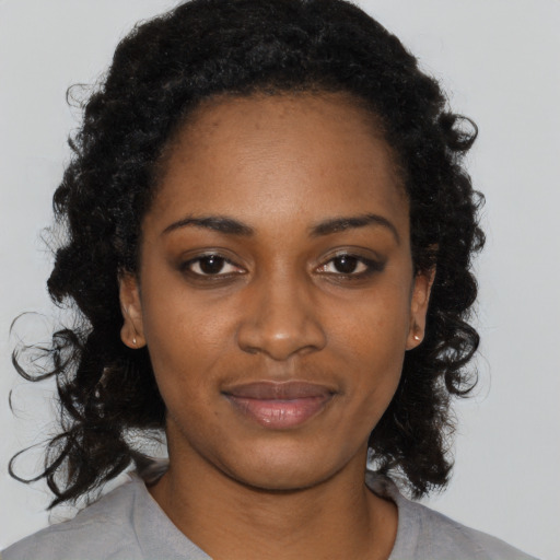 Joyful black young-adult female with long  black hair and brown eyes