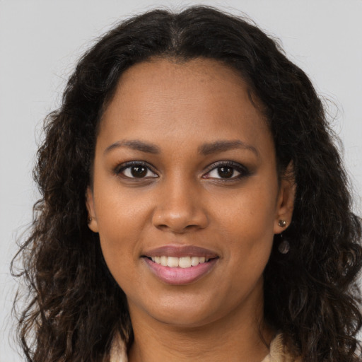 Joyful black young-adult female with long  brown hair and brown eyes