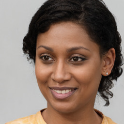 Joyful black young-adult female with long  brown hair and brown eyes