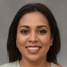 Joyful latino young-adult female with medium  brown hair and brown eyes