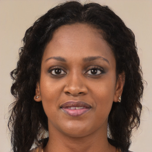 Joyful black young-adult female with long  brown hair and brown eyes
