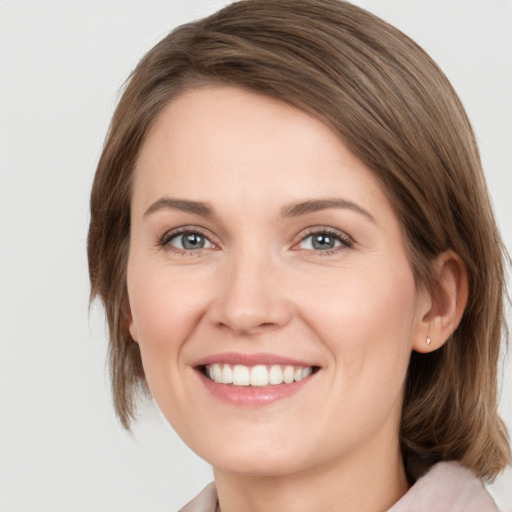 Joyful white young-adult female with medium  brown hair and grey eyes