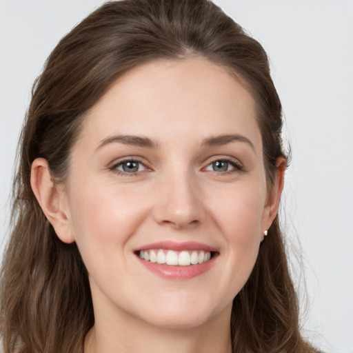 Joyful white young-adult female with long  brown hair and grey eyes