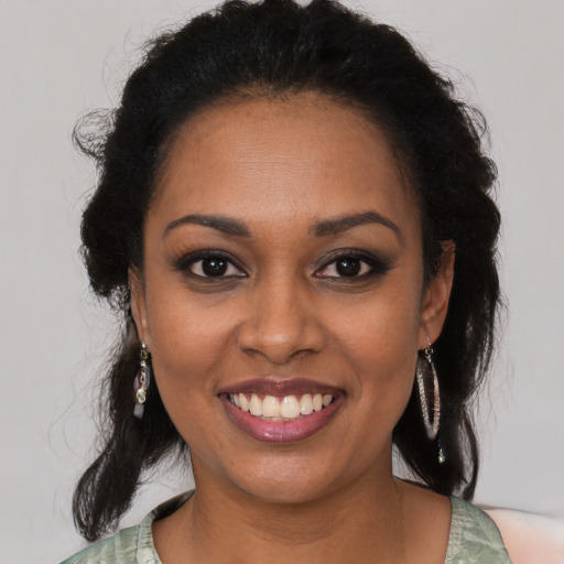 Joyful black young-adult female with long  brown hair and brown eyes