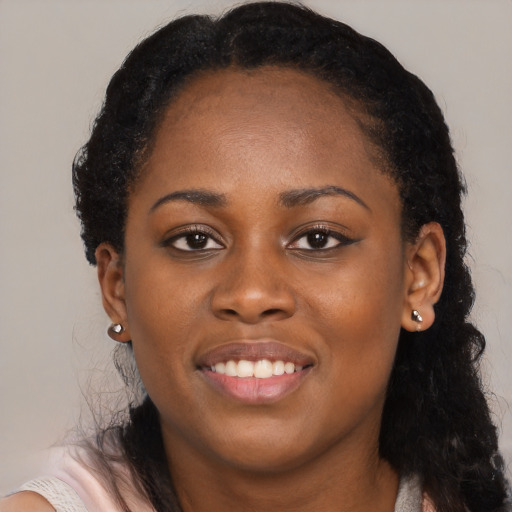 Joyful black young-adult female with long  black hair and brown eyes