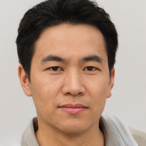 Joyful asian young-adult male with short  brown hair and brown eyes