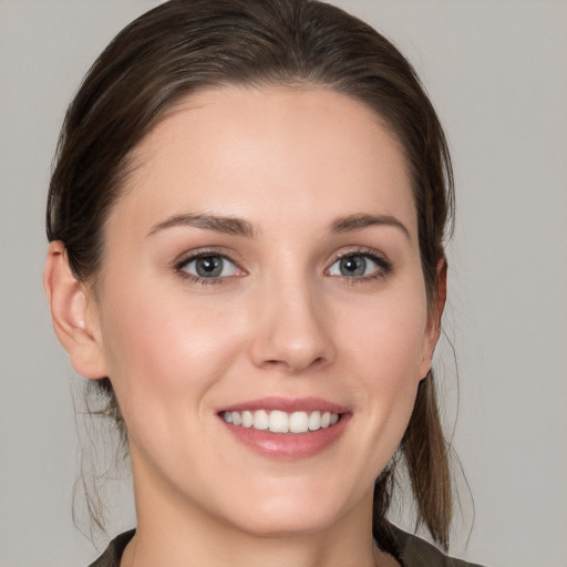 Joyful white young-adult female with medium  brown hair and grey eyes