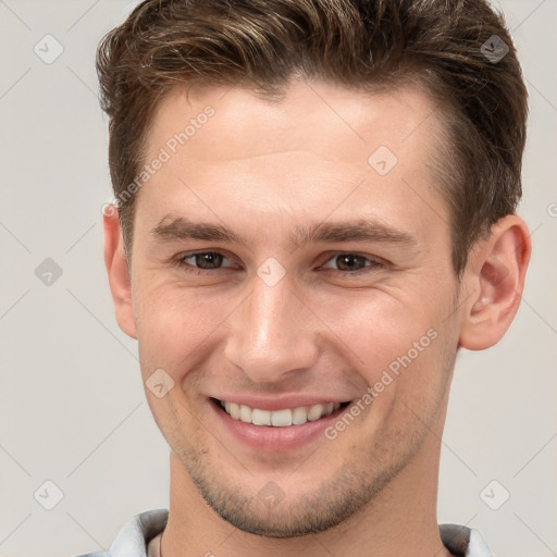 Joyful white young-adult male with short  brown hair and grey eyes