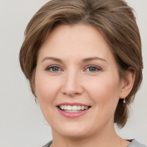 Joyful white young-adult female with medium  brown hair and grey eyes