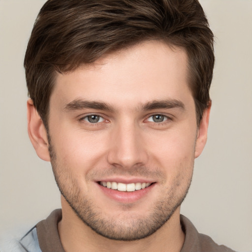 Joyful white young-adult male with short  brown hair and grey eyes