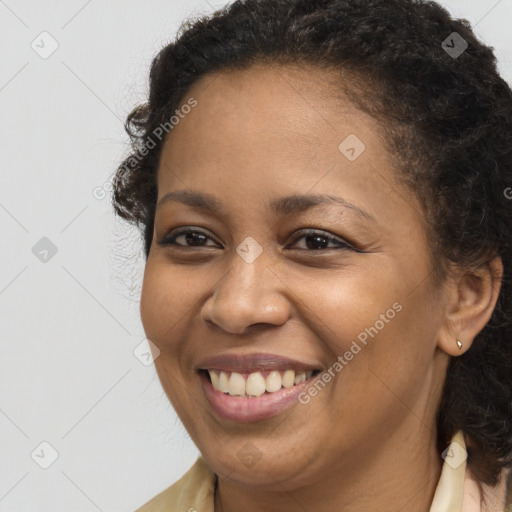 Joyful black young-adult female with long  brown hair and brown eyes